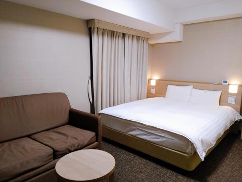 a hotel room with a bed and a couch at Dormy Inn Express Matsue in Matsue