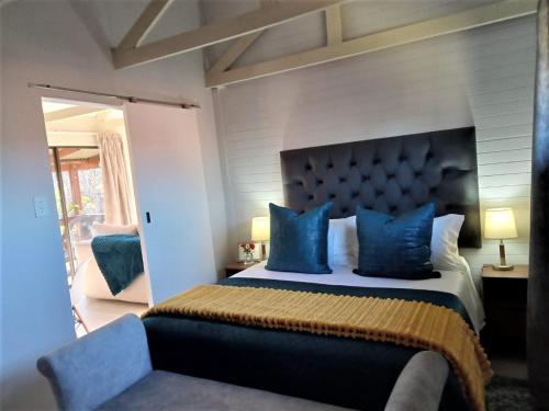 a bedroom with a king sized bed with blue pillows at Cinnamon & Sage Country Cabins in Dullstroom