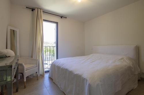 a white bedroom with a bed and a window at Villa Tica in Malaucène
