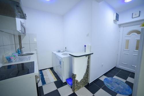 a small white kitchen with a black and white checkered floor at Apartman Kan in Bihać