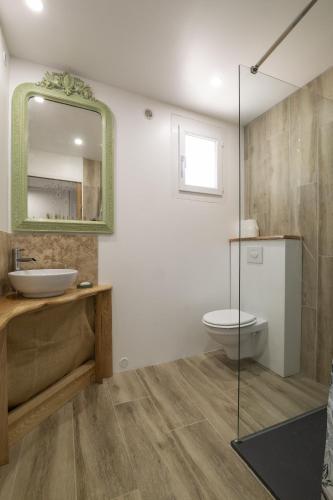 une salle de bain avec un lavabo, des toilettes et un miroir dans l'établissement Le Dali, à Piolenc