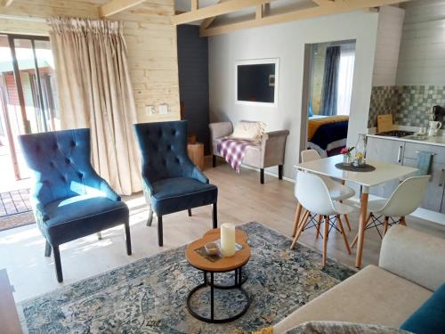 a living room with a couch and chairs and a table at Cinnamon & Sage Country Cabins in Dullstroom