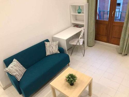 a living room with a blue couch and a table at Una genial estancia en el barrio las cortes in Madrid