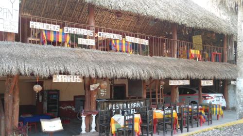 a restaurant with chairs and a straw roof at Hotel LOL-HA in Cobá