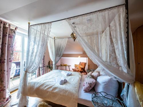 1 dormitorio con cama con dosel y ventana en Homely Stay in a romantic lodging with sauna&gym, en Münsing
