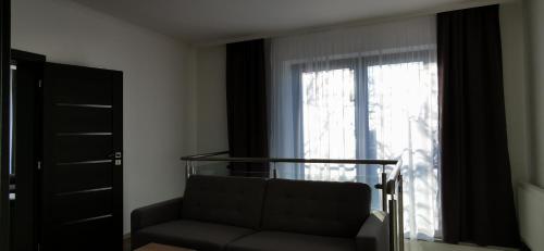 - un salon avec un canapé et une fenêtre dans l'établissement Apartmány Pavlík, à Nesvady