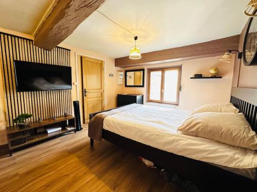 une chambre avec un grand lit et une télévision à écran plat dans l'établissement Le Refuge, à Laon