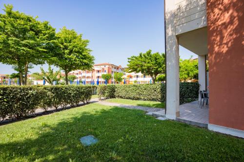 a yard with grass and trees next to a building at Pini Village Lido Altanea in Caorle