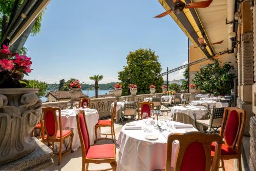 a restaurant with white tables and red chairs at Hotel Laurin in Salò