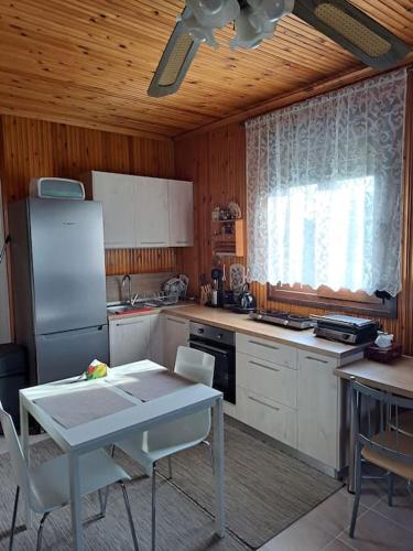 a kitchen with a refrigerator and a table with chairs at Μονοκατοικία Kathrin in Nea Kalikratia