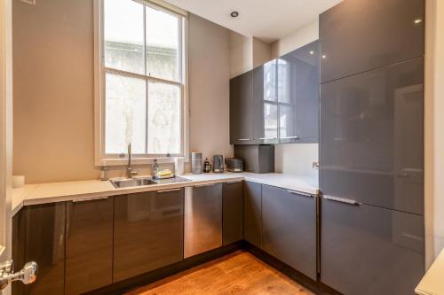 a kitchen with stainless steel cabinets and a window at Canal Crescent Charm Flat with Stunning Views Little Venice in London