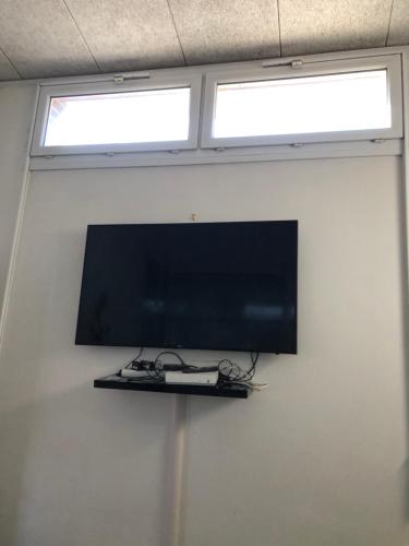 einen Flachbild-TV an einer Wand mit zwei Fenstern in der Unterkunft Chatif in Agadir