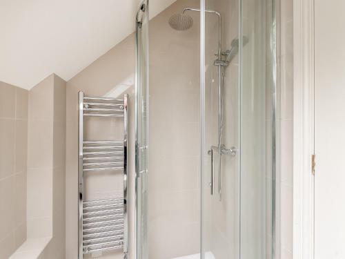 um chuveiro com uma porta de vidro na casa de banho em The Coach House em Ingoldsby