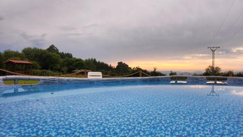 a large swimming pool with a sunset in the background at La cabaña de Seña in Laredo