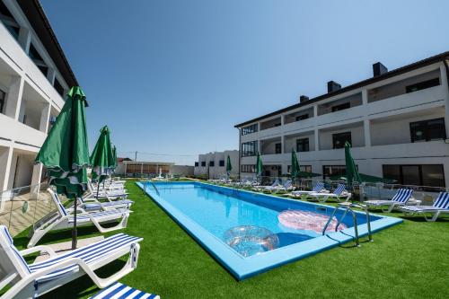 a swimming pool with lawn chairs and umbrellas at Weekend Family Hotel in Karolino-Buhaz