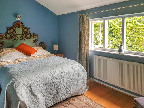 a bedroom with a bed with blue walls and windows at Coach House in Ashford
