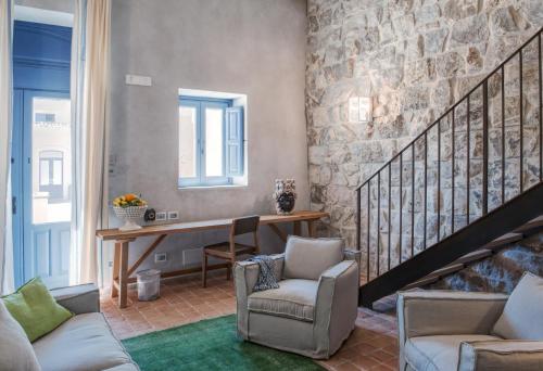 a living room with a table and chairs and a stone wall at Masseria Della Volpe in Casale Modica