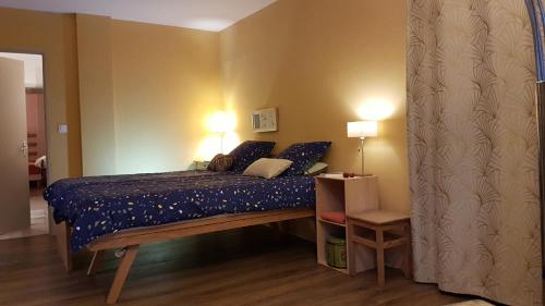 a bedroom with a bed with blue sheets and pillows at Aux Couleurs Miel in Montolieu