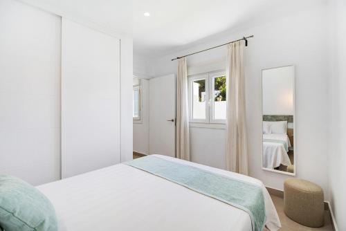 Habitación blanca con cama y espejo en Casa Piscina Cubierta Climatizada 3, en Chiclana de la Frontera
