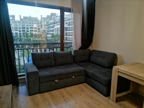 ein Sofa im Wohnzimmer mit einem großen Fenster in der Unterkunft Апартамент Релакс in Goldstrand