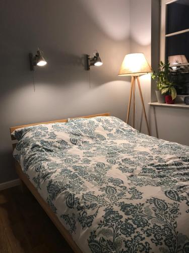 1 cama con edredón azul y blanco y lámpara en Apartament Święty Wojciech, en Gdansk
