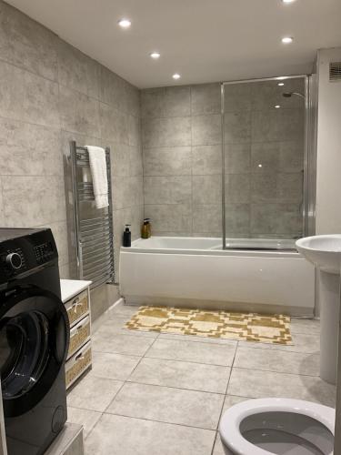 a bathroom with a tub and a sink and a washing machine at Rock Studio -Near City Centre-Free on street Parking-Free Wi-Fi in Leeds