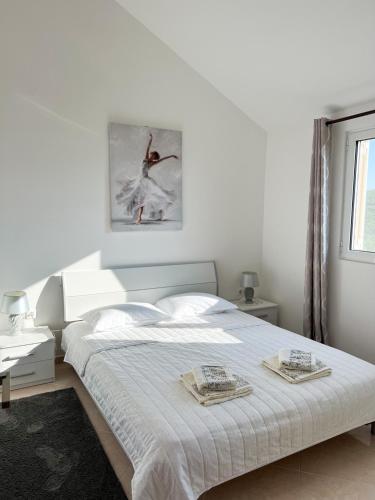a white bedroom with a bed with two towels on it at Villa Pari Apartment in Kotor