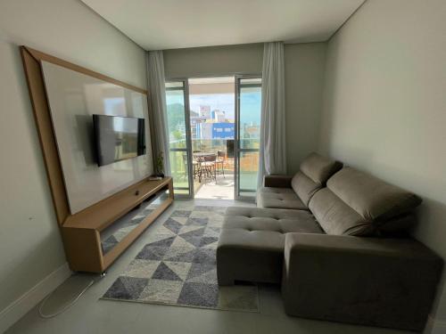 ein Wohnzimmer mit einem Sofa und einem Flachbild-TV in der Unterkunft Apartamento com vista mar prox ao mercado in Governador Celso Ramos