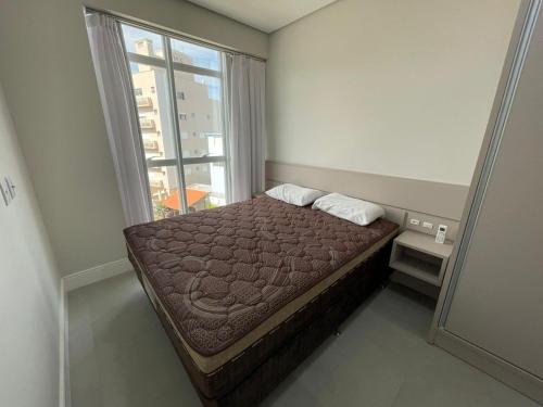 ein kleines Schlafzimmer mit einem Bett und einem Fenster in der Unterkunft Apartamento com vista mar prox ao mercado in Governador Celso Ramos