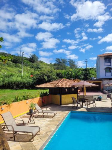 un patio con piscina, sillas y mesa en Thetis Hotel Pousada, en Arraial do Cabo