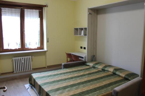 um quarto com uma cama, uma mesa e uma janela em Residence La Noce con Angolo Cottura em Chivasso