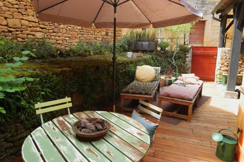 une terrasse avec une table, des chaises et un parasol dans l'établissement La Maisonnette de La Jolie Vie, à Urval