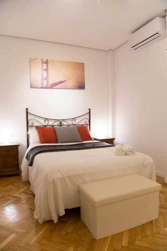マドリードにあるUn Elegante Piso Para Descubrir Madridのベッドルーム1室(大型ベッド1台、ベンチ付)
