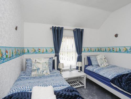 two beds in a room with blue and white at Morlais Voice of the Sea in Aberffraw