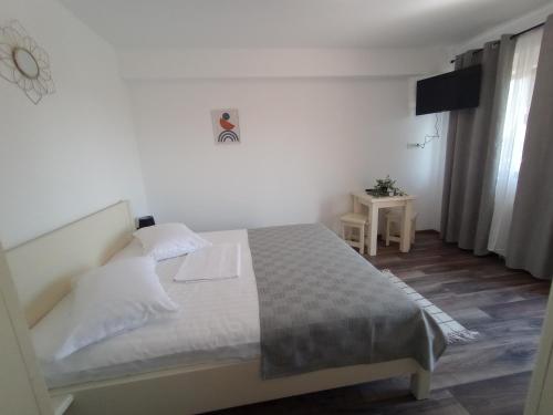 ein Schlafzimmer mit einem weißen Bett und einem Tisch in der Unterkunft Pestele Ca Odinioară in Murighiol