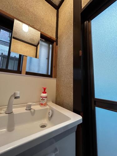 a bathroom with a white sink and a mirror at 1970's Japanese style dorm house in Tokyo