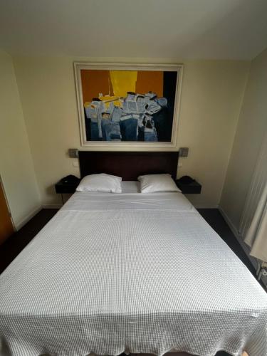 uma cama branca num quarto com uma pintura na parede em Hôtel Tingis em Paris