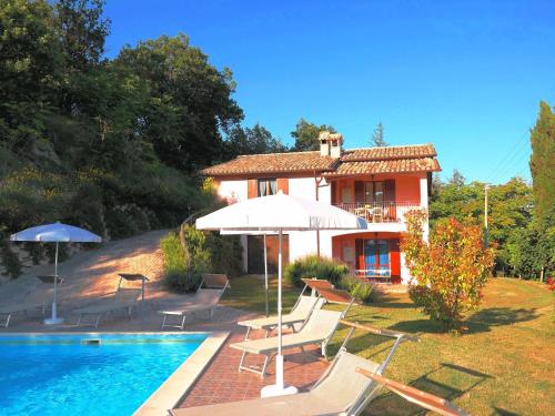 a house with a pool and chairs and an umbrella at Luxurious Villa in Acqualagna with Swimming Pool in Acqualagna