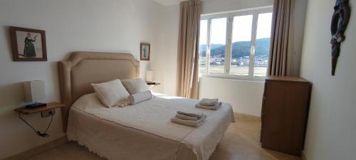 1 dormitorio con 1 cama con toallas en PISO EN MUROS (VIRGEN 3), en Muros