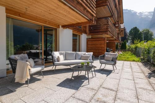 a patio with two couches and a table and chairs at The Terrace Apartment - GRINDELHOMES in Grindelwald