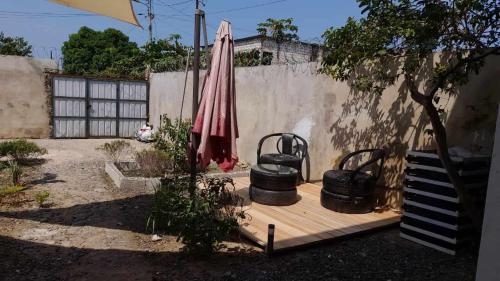 eine Terrasse mit einem Regenschirm und einigen Töpfen und einem Zaun in der Unterkunft Hostel Sao Gabriel in São Tomé
