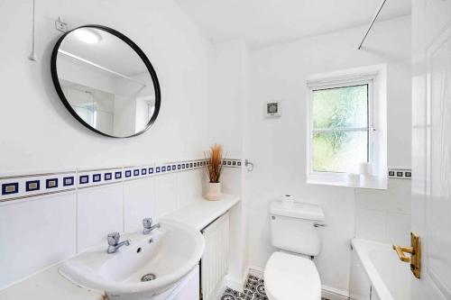 ein weißes Badezimmer mit einem Waschbecken und einem Spiegel in der Unterkunft The Nora - 4 Bed in Thamesmead