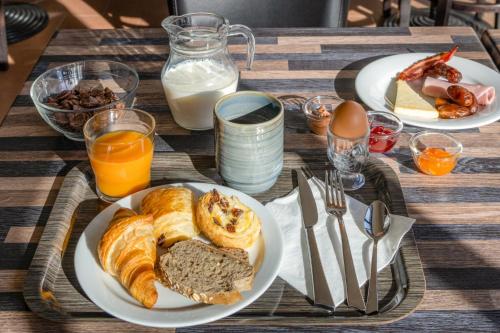 a table topped with plates of breakfast foods and orange juice at Hôtel La Nartelle in Sainte-Maxime