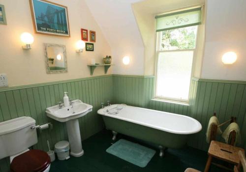 a green bathroom with a tub and a sink at Cluny Mains in Newtonmore