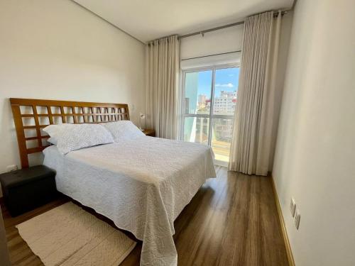 a bedroom with a bed and a large window at Apartamento Prime Master Collection in Passo Fundo