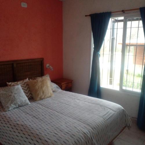 a bedroom with a bed with blue curtains and a window at PUEBLO MIO in Cosquín