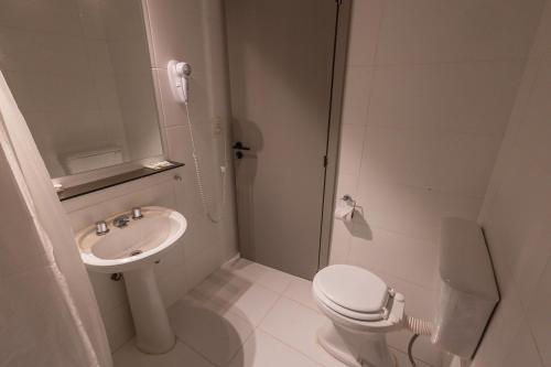 a white bathroom with a toilet and a sink at Tierra Gaucha Hostel Boutique in San Carlos de Bariloche