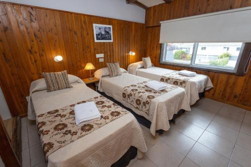 a hotel room with three beds and a window at Tierra Gaucha Hostel Boutique in San Carlos de Bariloche
