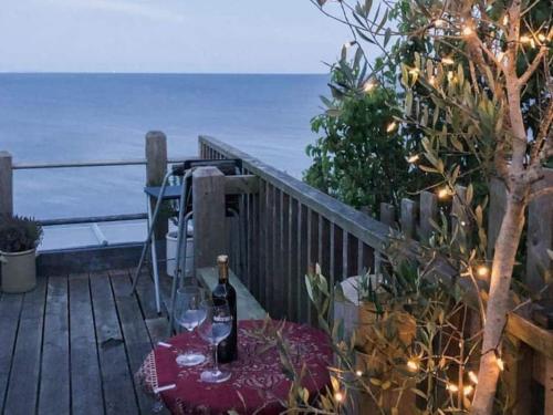 - une table avec des verres à vin et des lumières sur le balcon dans l'établissement Lyme Clifftop Hideaway, à Lyme Regis