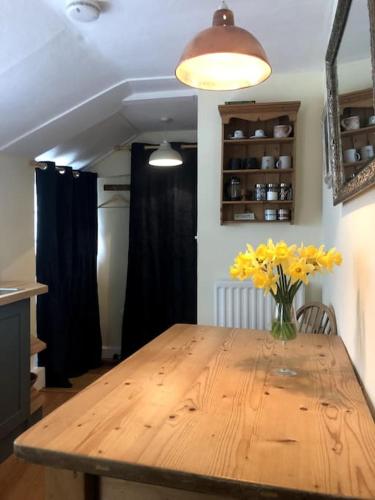 a wooden table with a vase of yellow flowers on it at Lyme Clifftop Hideaway in Lyme Regis